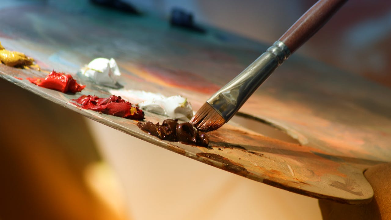 Artist's palette with colorful paint and brushes on a wooden surface