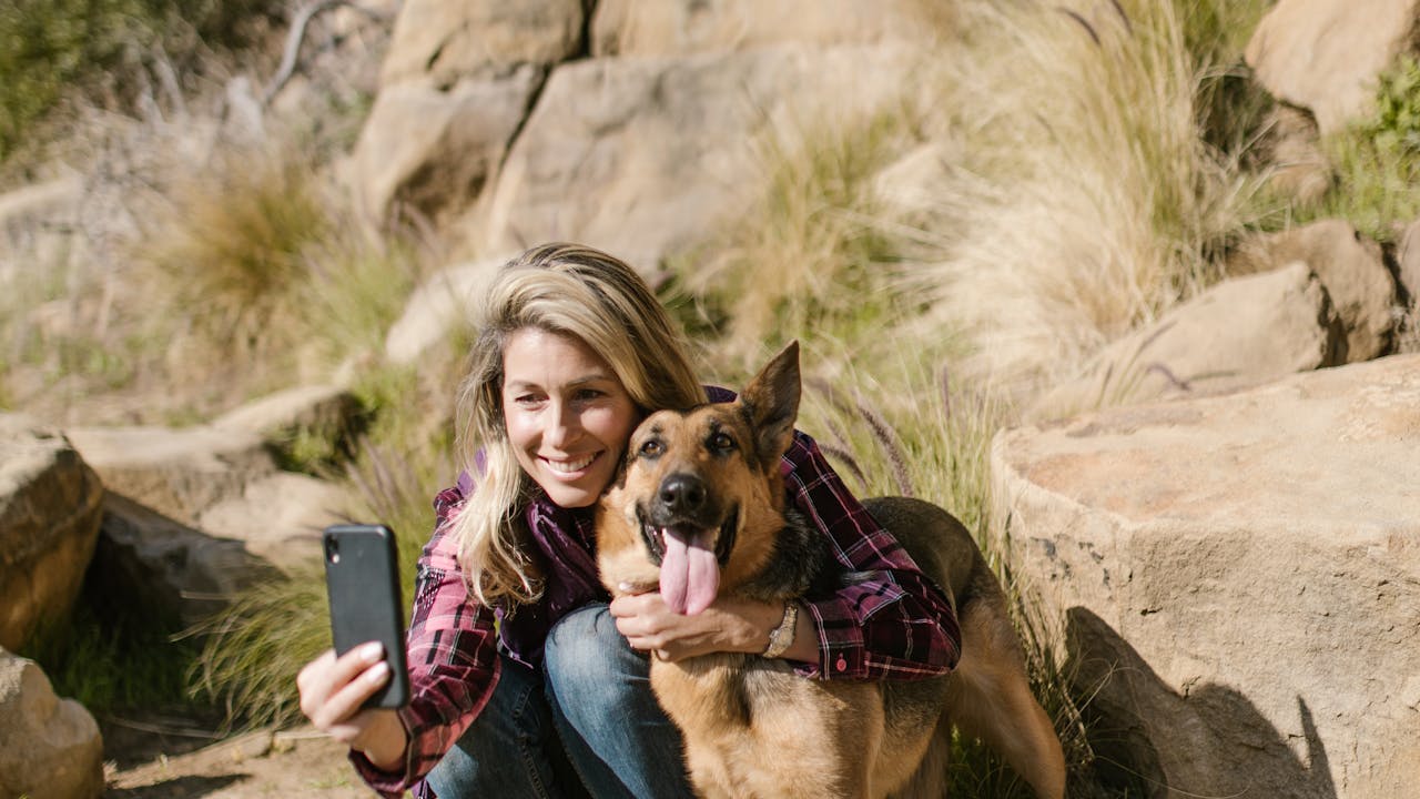 Pet owner photographing their dog outdoors in natural daylight