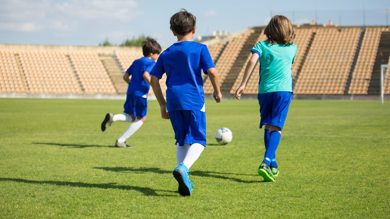 Kids playing soccer together on a sunny field