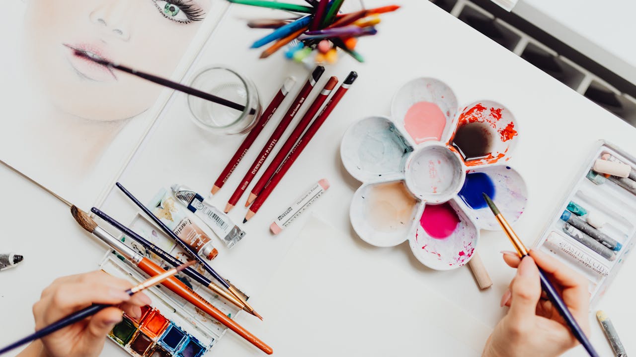 Art supplies including brushes, paints, and pencils arranged on a creative workspace