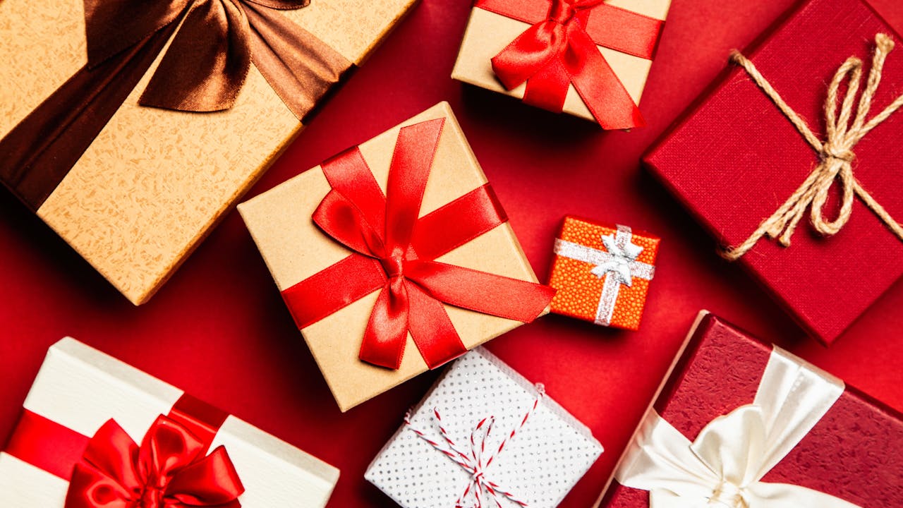Wrapped gift boxes with ribbons in red and gold tones on a festive background