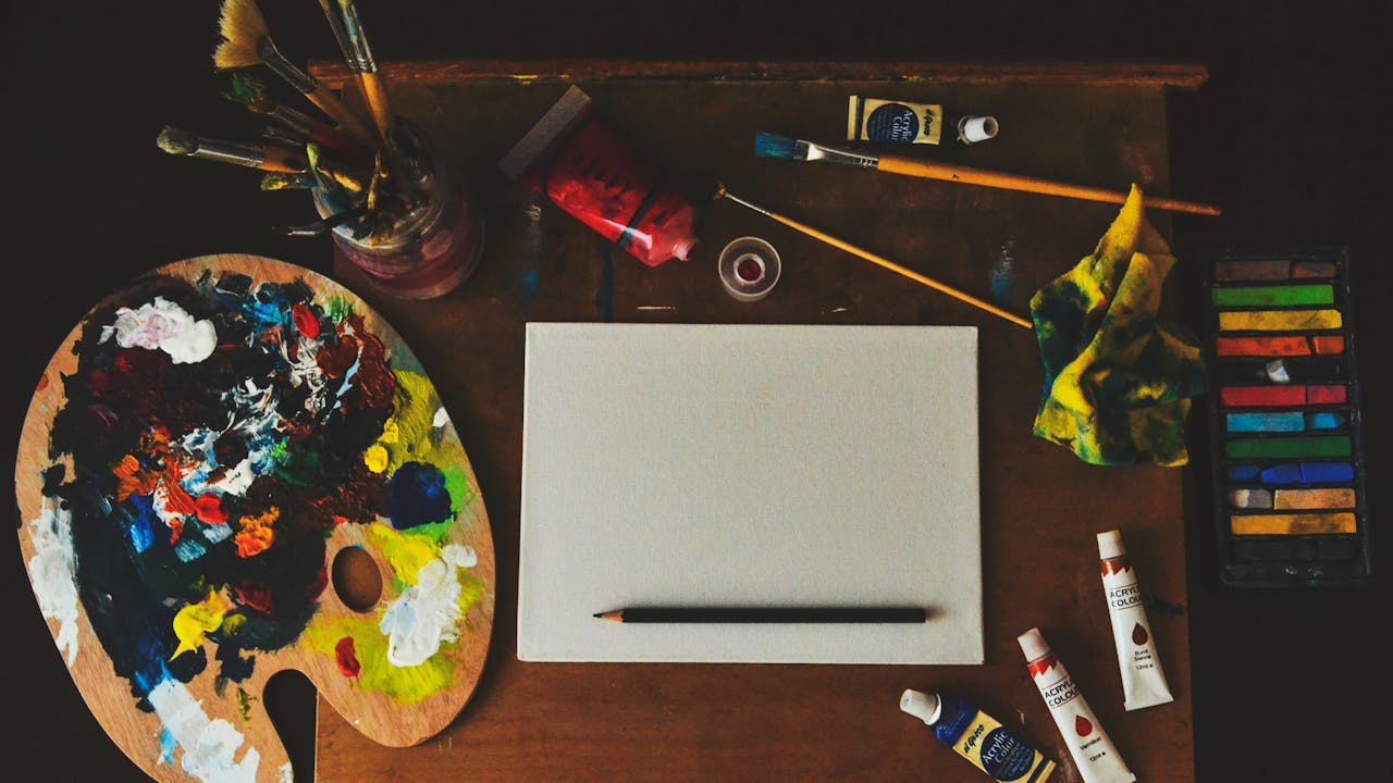 Classical portrait drawing pencils and charcoal tools laid out on a wooden desk