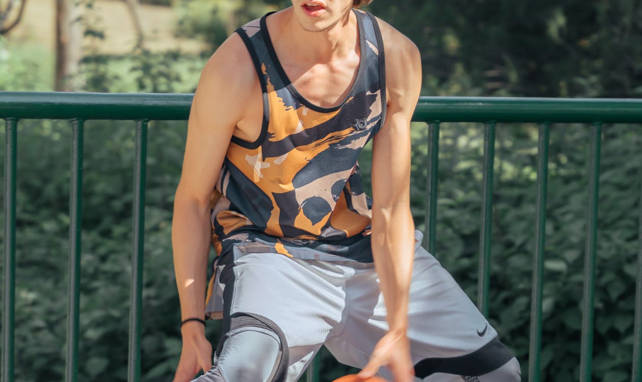 Young man with basketball during senior portrait session at outdoor court